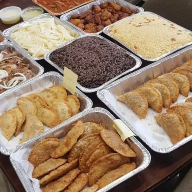 Catering trays of empanadas, moro, yellow rice, yuca and roast pork with onions